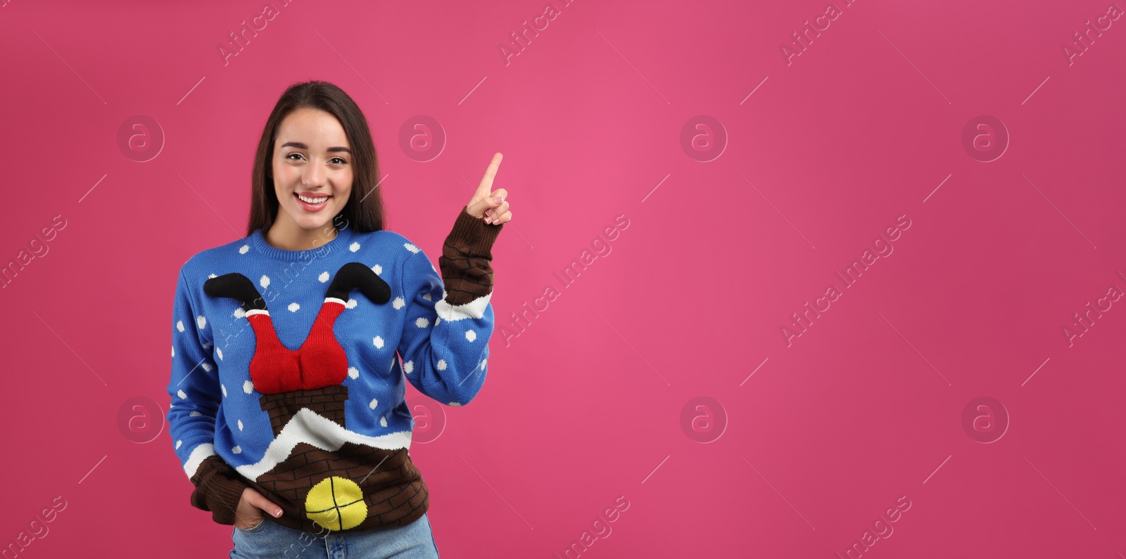 Photo of Young woman in Christmas sweater on pink background, space for text