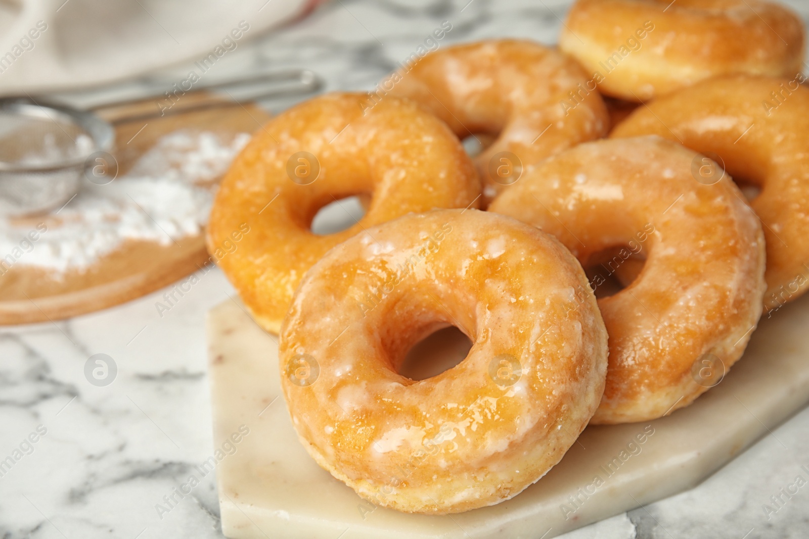 Photo of Delicious glazed donuts on marble table, closeup