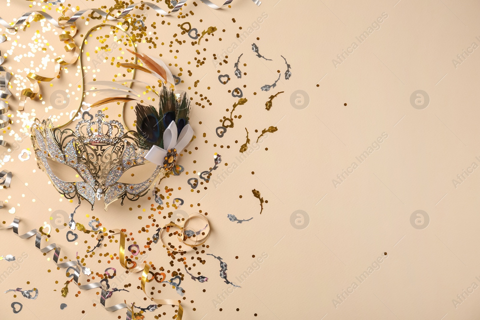Photo of Beautiful carnival mask and party decor on beige background, flat lay. Space for text