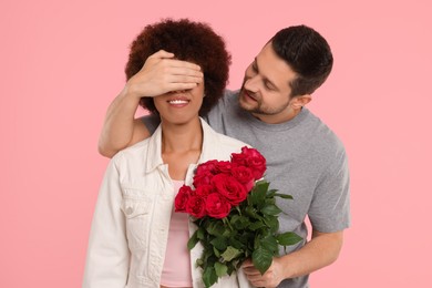 International dating. Handsome man presenting roses to his beloved woman on pink background