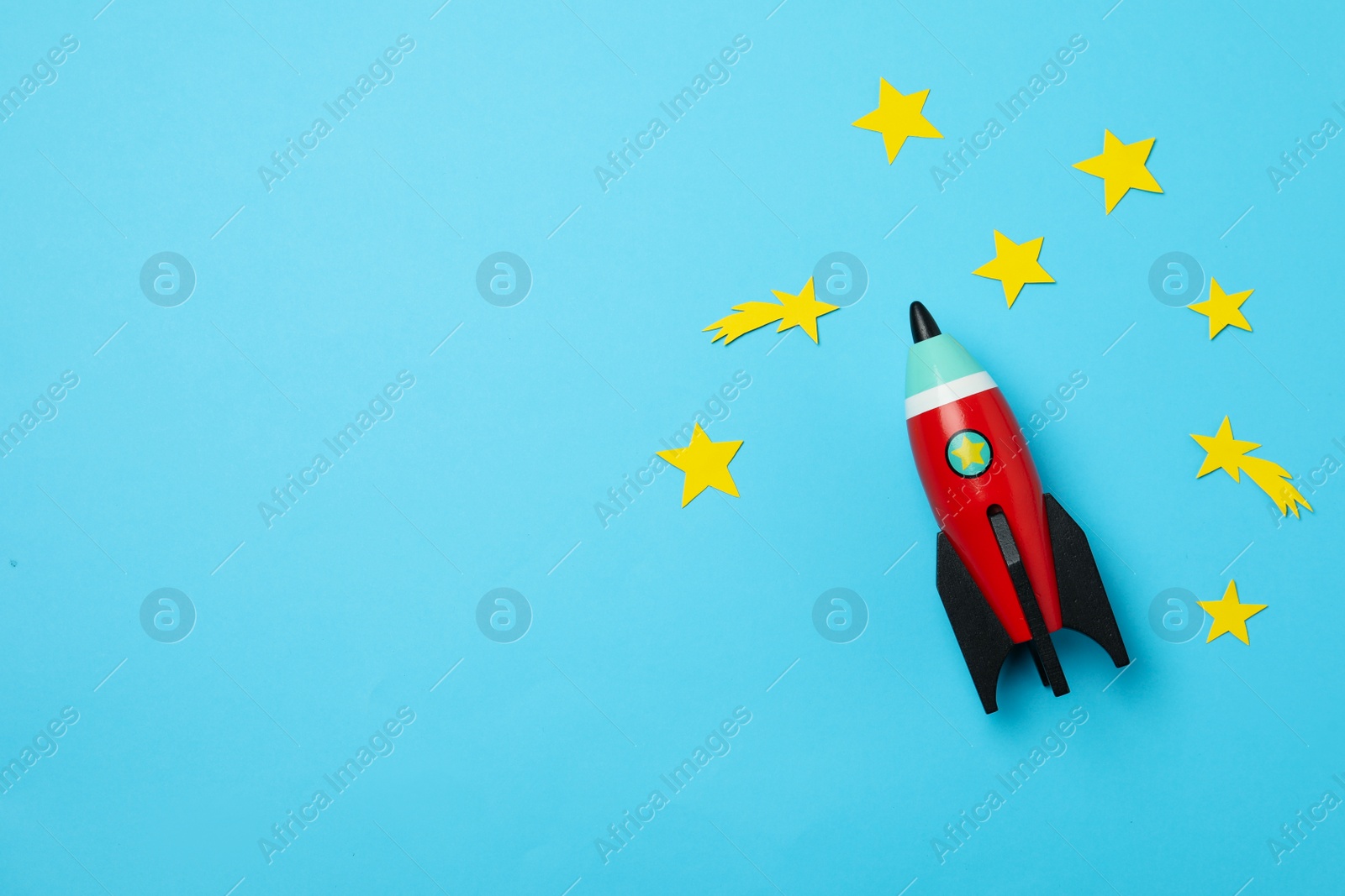 Photo of Bright toy rocket and stars on light blue background, flat lay. Space for text