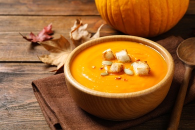 Bowl with tasty pumpkin cream soup on wooden table