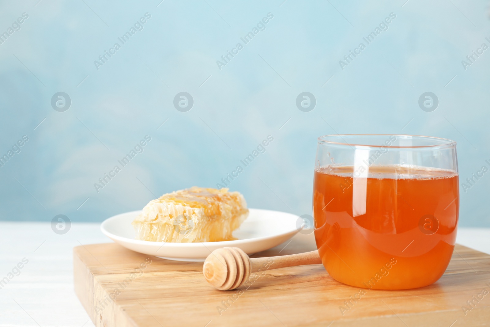 Photo of Glass jar with sweet honey and dipper on table, closeup