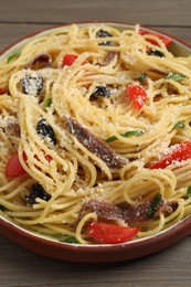 Photo of Plate of delicious pasta with anchovies, tomatoes and parmesan cheese on wooden table, closeup