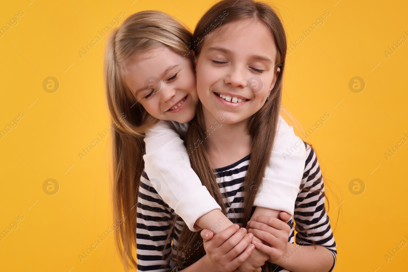 Photo of Portrait of cute little sisters on orange background