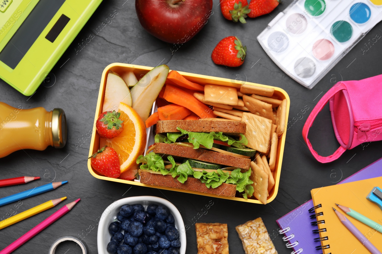 Photo of Flat lay composition with lunch box, tasty healthy food and school stationery on grey table