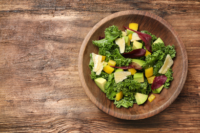 Photo of Delicious kale salad served on wooden table, top view. Space for text