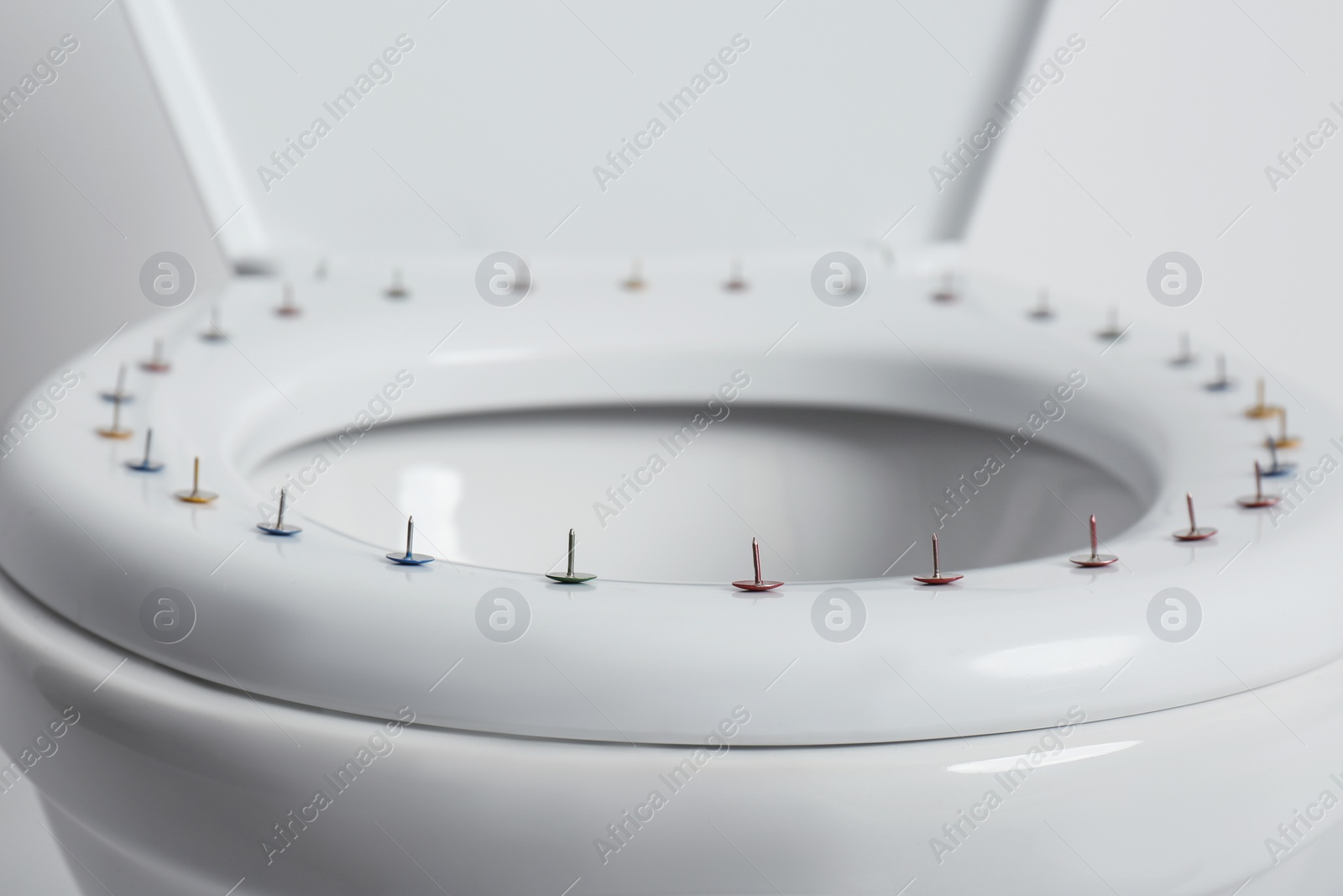 Photo of Toilet bowl with pins on white background, closeup. Hemorrhoids concept