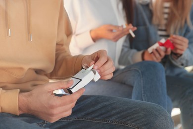 Photo of Man taking cigarette out of pack outdoors, closeup