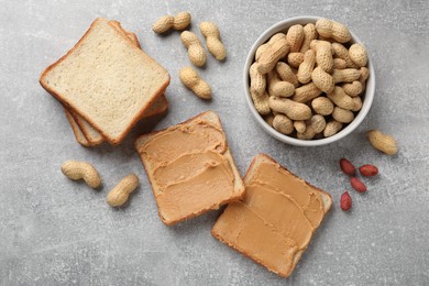 Photo of Tasty peanut butter sandwiches and peanuts on gray table, flat lay