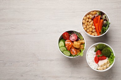 Different healthy meals in paper containers on white wooden table, flat lay. Space for text