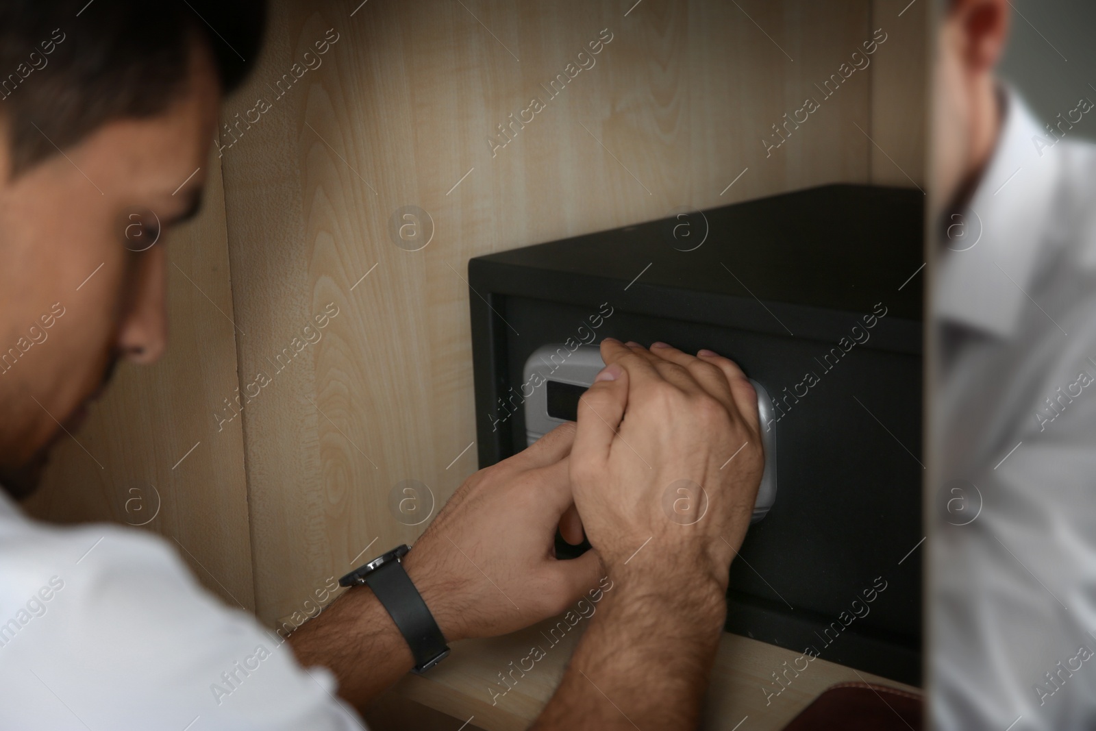 Photo of Man opening black steel safe with electronic lock at hotel, closeup