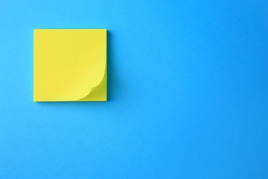 Photo of Blank paper note on light blue background, top view. Space for text