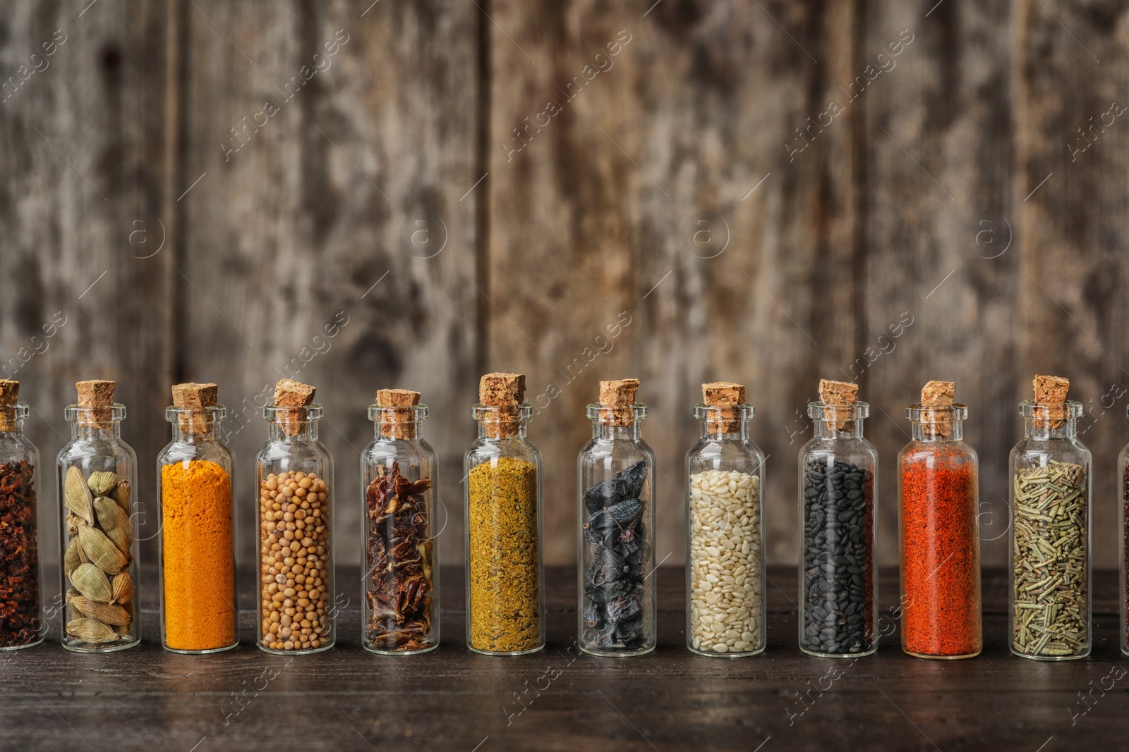 Photo of Bottles with different spices on table against blurred background