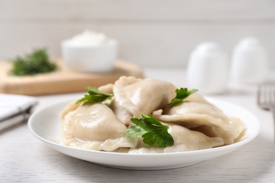 Photo of Plate of tasty cooked dumplings served on white wooden table