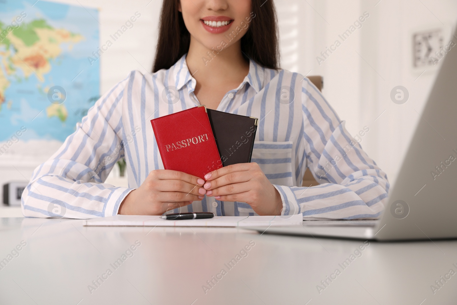 Photo of Happy manager holding passports at desk in travel agency, closeup