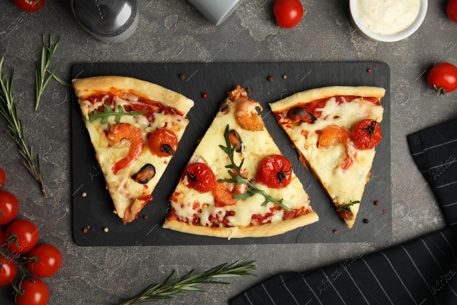 Photo of Pieces of delicious seafood pizza on grey table, flat lay