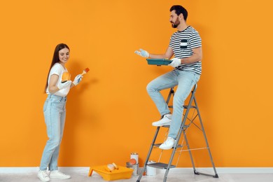Photo of Designers with painting equipment near freshly painted wall indoors