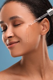Photo of Beautiful woman applying serum onto her face, closeup