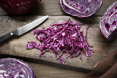 Photo of Delicious fresh shredded red cabbage and knife on wooden table