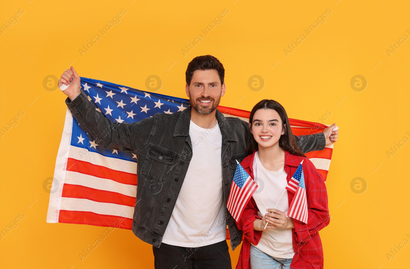 Photo of 4th of July - Independence Day of USA. Happy man and his daughter with American flags on yellow background