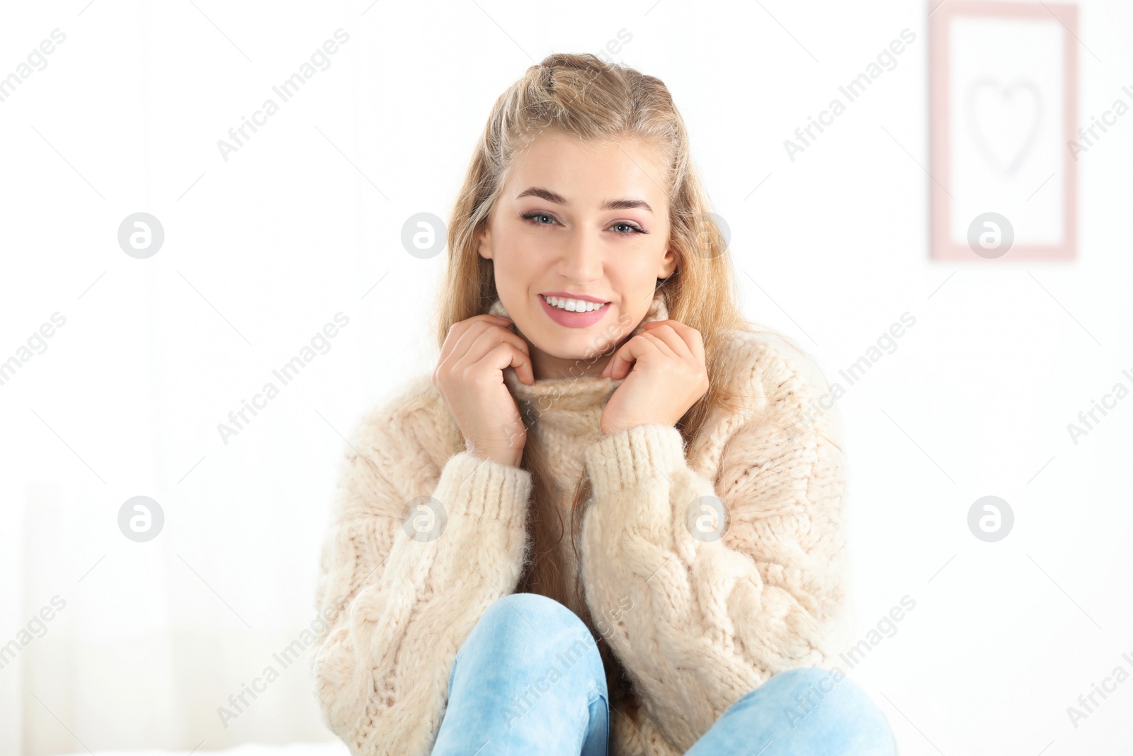 Photo of Beautiful smiling young woman in cozy warm sweater at home