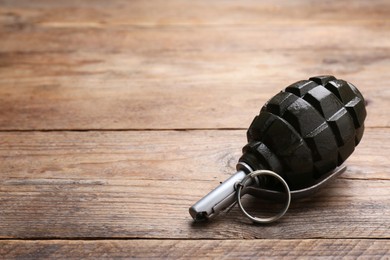 Photo of Hand grenade on wooden table, closeup. Space for text