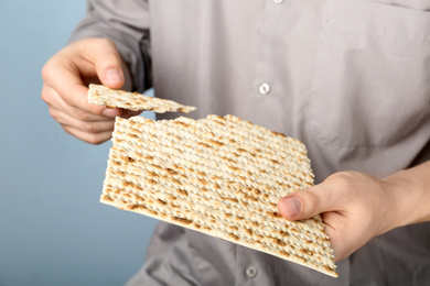 Man with Matzo on grey background, closeup. Pesach (Passover) celebration