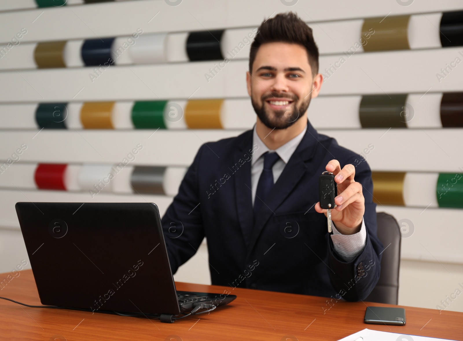 Photo of Salesman with car key at desk in office