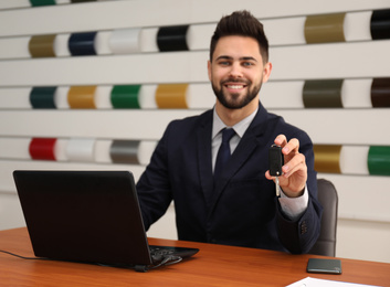 Salesman with car key at desk in office