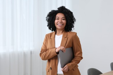 Photo of Smiling young businesswoman with laptop in office