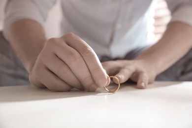 Image of Man with wedding ring at table indoors, closeup. Cheating and breakup