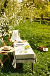 Photo of Stylish table setting with beautiful spring flowers in garden on sunny day