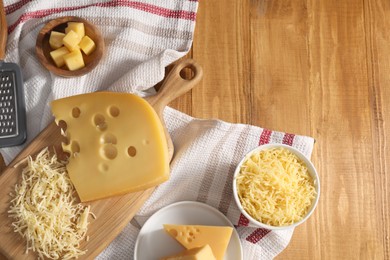 Grated, cut cheese and grater on wooden table, flat lay. Space for text