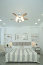 Photo of Comfortable furniture, ceiling fan, houseplants and accessories in stylish bedroom