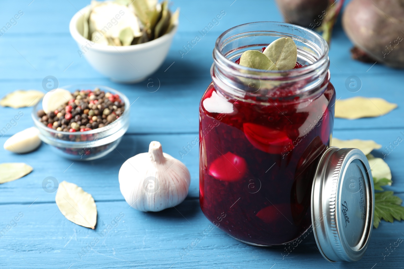 Photo of Pickled beets in glass jar on light blue wooden table