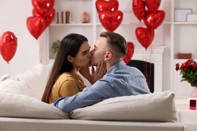 Photo of Lovely couple kissing on sofa at home. Valentine's day celebration