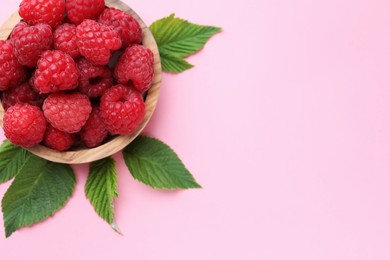 Photo of Tasty ripe raspberries and green leaves on pink background, above view. Space for text