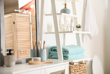 Fresh towels on decorative ladder in modern bathroom