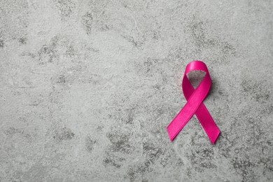 Photo of Pink ribbon on grey table, top view with space for text. Breast cancer awareness concept