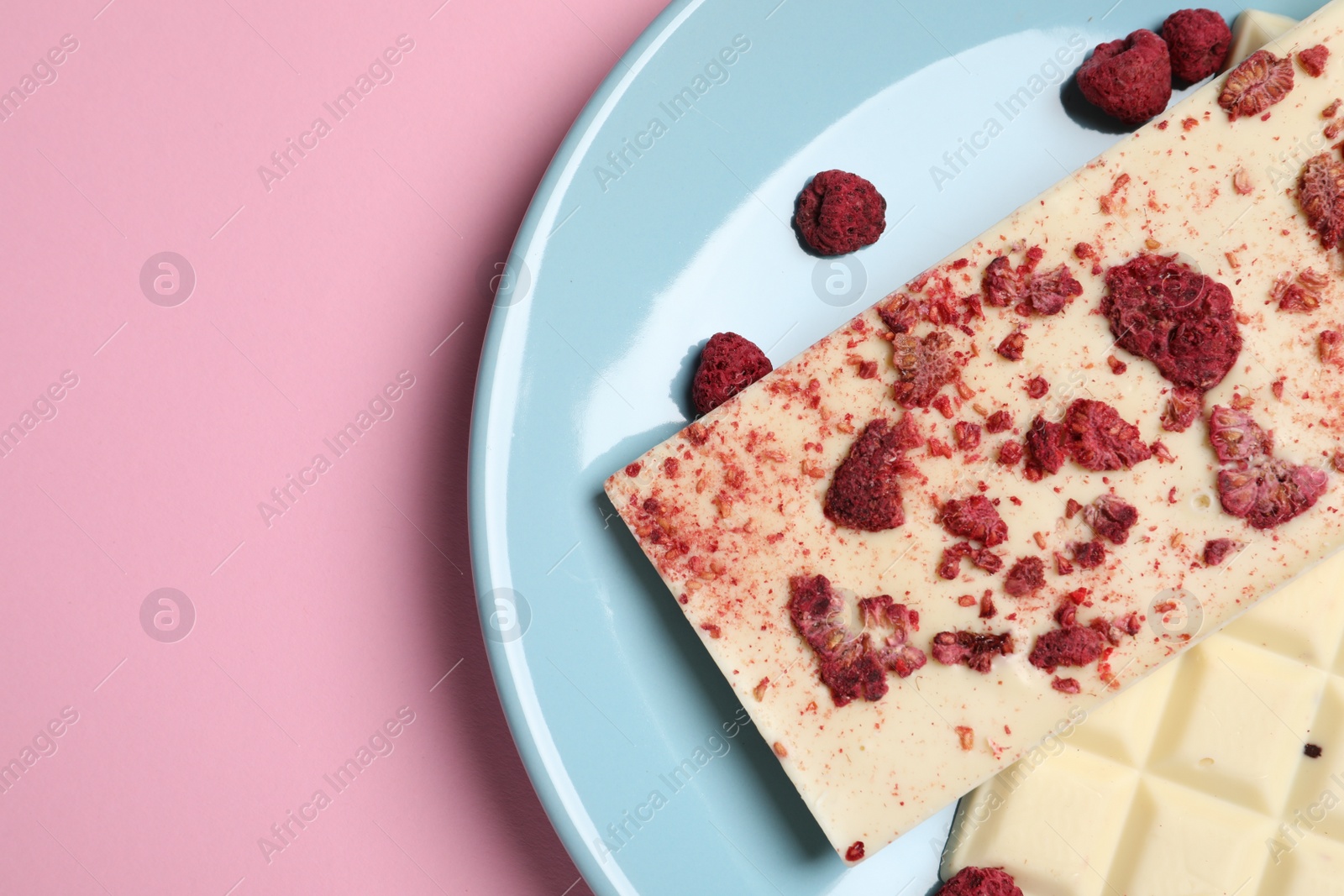 Photo of White chocolate with freeze dried fruits on pink background, top view. Space for text