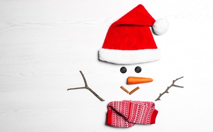 Photo of Funny snowman made with different elements on white wooden background, flat lay