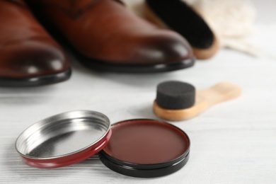 Photo of Shoe care products and footwear on white table, closeup