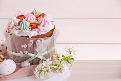 Photo of Traditional Easter cake with meringues and painted eggs on white wooden table, space for text