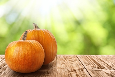 Wooden table with fresh pumpkins outdoors on sunny day. Space for text