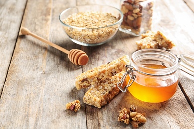 Photo of Homemade grain cereal bars and honey on wooden table. Healthy snack