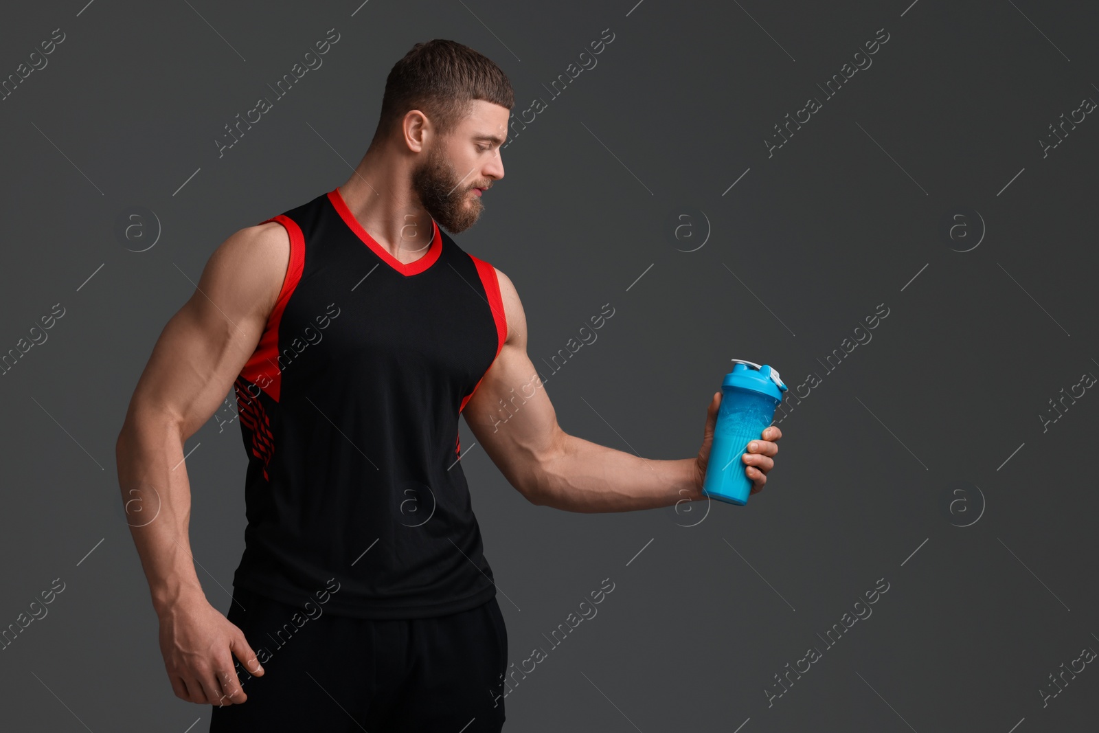 Photo of Young man with muscular body holding shaker of protein on grey background, space for text