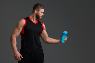 Young man with muscular body holding shaker of protein on grey background, space for text
