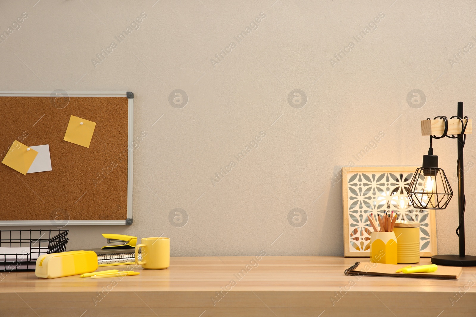 Photo of Stylish workplace with stationery on wooden desk near light wall. Interior design