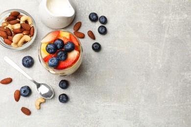 Photo of Delicious fruit salad, fresh berries and nuts on light grey table, flat lay. Space for text